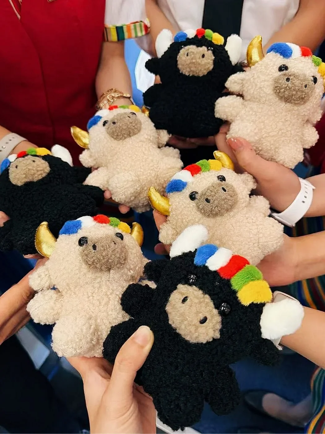 Many hands holding a whole herd of Tashi and Dele plush yaks together — 好多雙手一起捧著一大群扎西與德勒